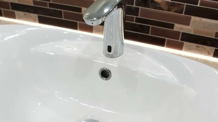 White vessel sink with a touchless chrome faucet and glass tile backsplash inside a Trash Rangers restroom trailer