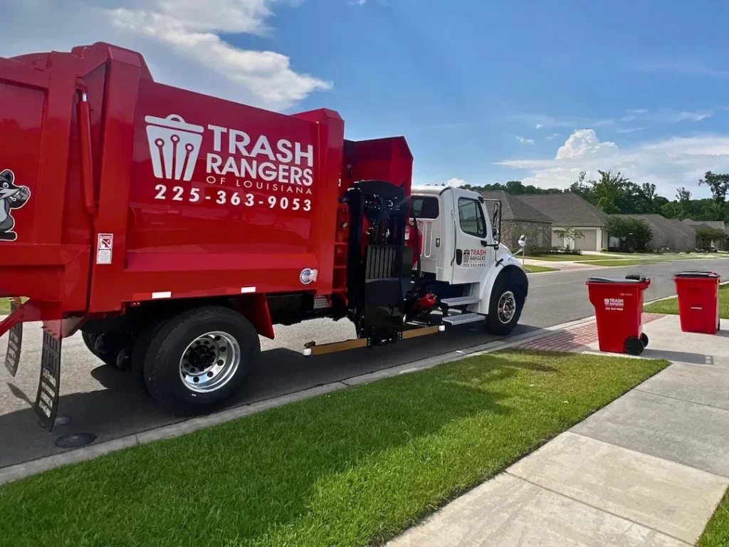 Red Trash Rangers residential garbage truck stopped at the curb beside two red Trash Rangers carts in a Louisiana neighborhood